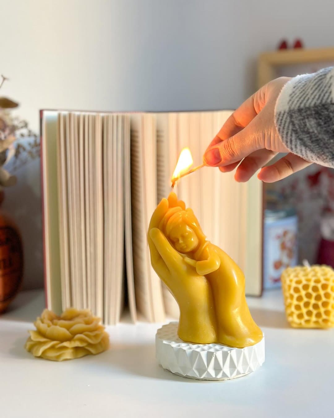 BeeQuite, a sculpted beeswax candle of a hand cradling a child